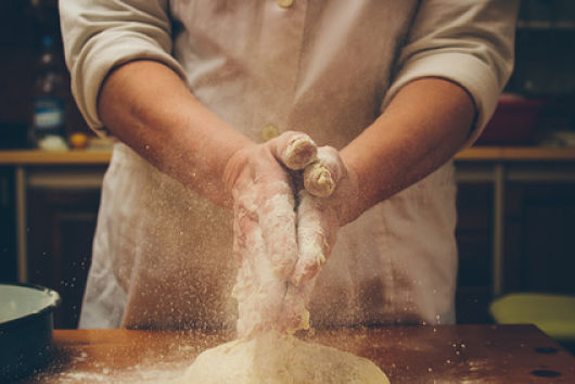 Chef clapping hands full of flour over fresh dough